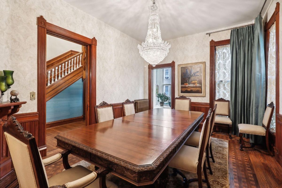 Formal dining room features a large, ornately carved wooden table, chairs, and a chandelier.