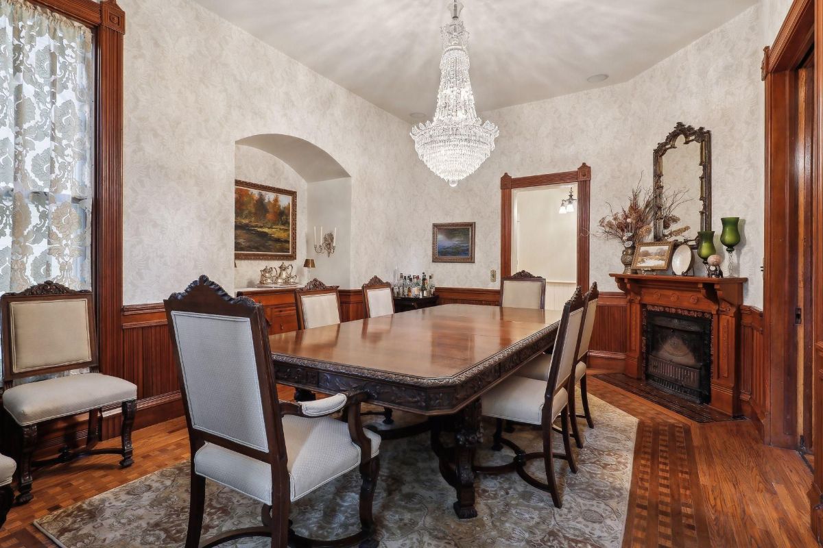 Elegant dining room is highlighted by a large, dark wood table, upholstered chairs, and a crystal chandelier.