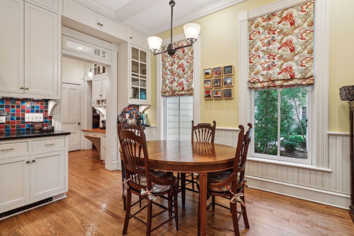 Bright kitchen features a round dining table with chairs, and colorful backsplash tile.