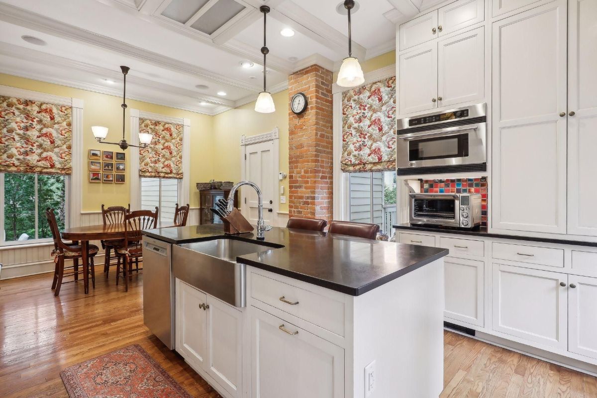 Kitchen boasts a large island with a farmhouse sink, white cabinetry, and patterned window treatments.