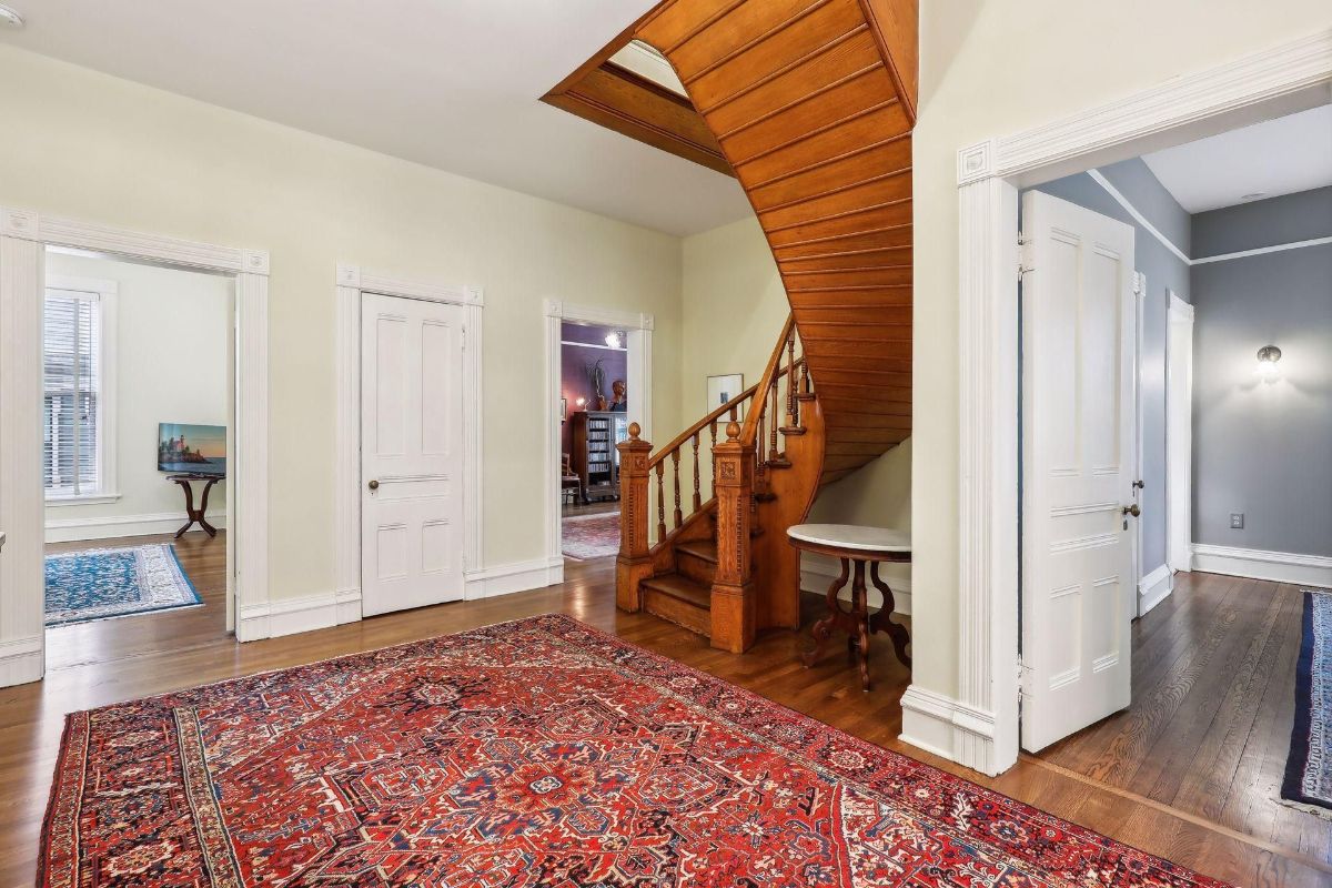 Hallway with a curved staircase and an area rug is shown.