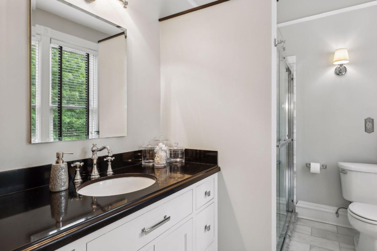 Bathroom with a dark countertop, white cabinets, and a sink