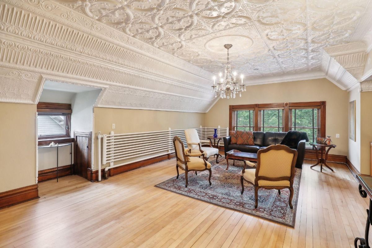 Room with hardwood floors, ornate ceiling, chandelier, and comfortable seating.