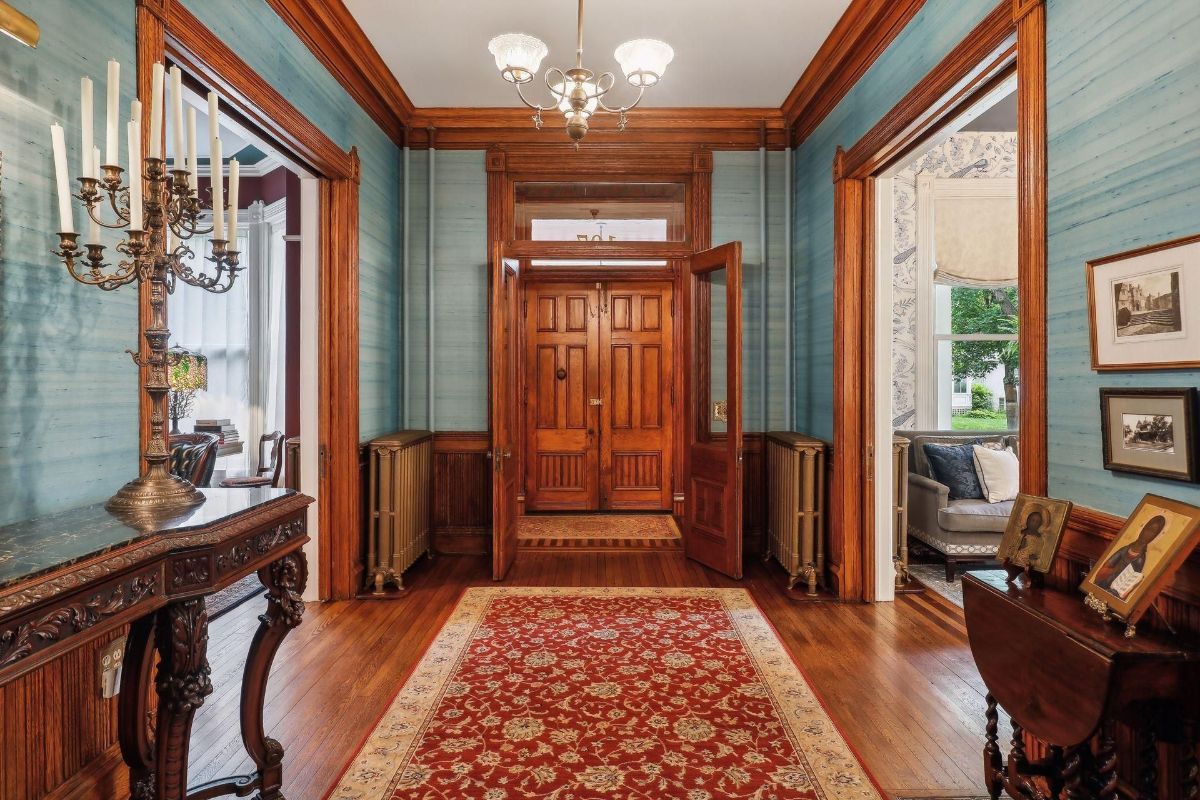 Grand entryway features dark wood trim, teal walls, and an ornate candelabra.