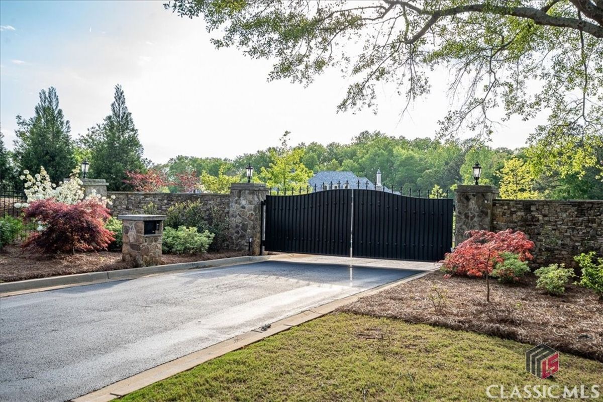 An elegant gated entrance framed by stone pillars and lush landscaping offers privacy and sophistication.