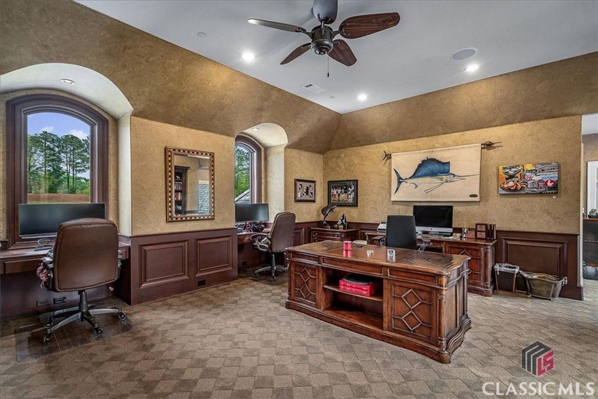 A spacious and elegant home office featuring rich wood paneling, vaulted ceilings, and multiple workstations designed for productivity.