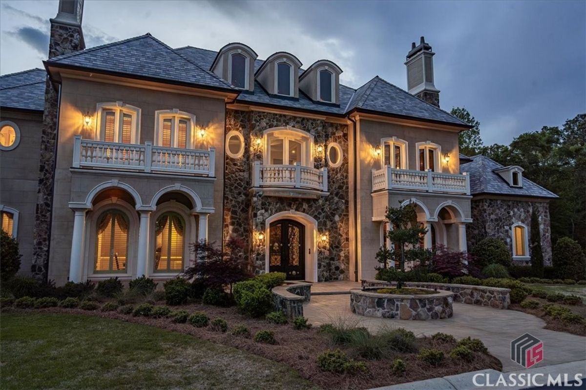 Illuminated elegance radiates from the intricately designed stone and stucco facade, enhanced by arched windows and sophisticated balconies.