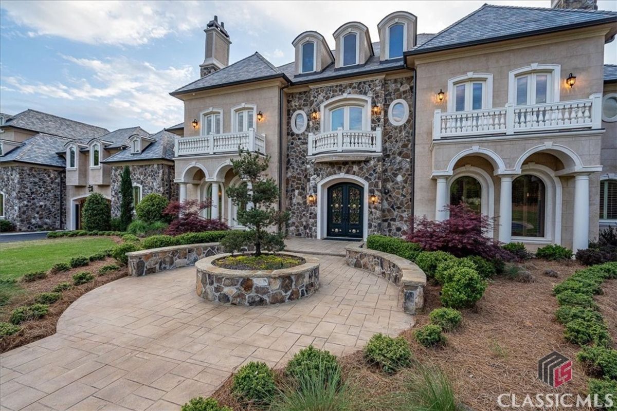 A stately facade featuring stone accents, arched windows, and balconies exudes European charm and timeless elegance.