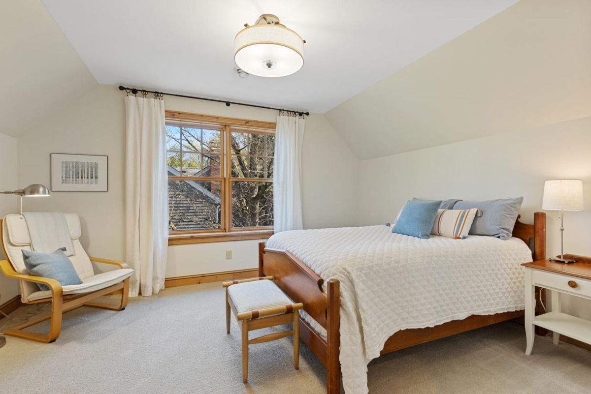 Cozy bedroom offers soft natural light, simple furnishings, and a serene neutral color palette.