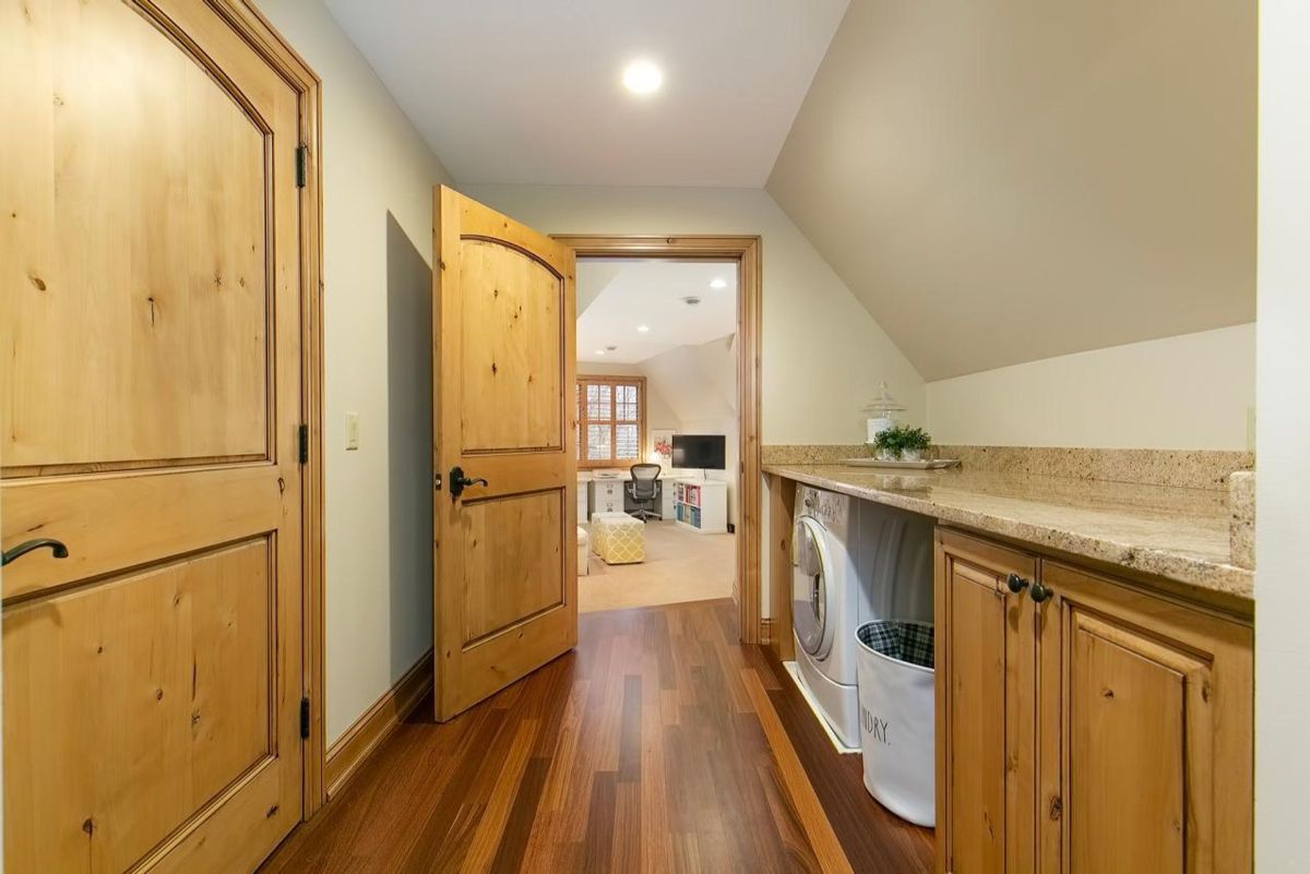 Compact laundry area features built-in cabinets, granite countertops, and seamless access to a multipurpose room.