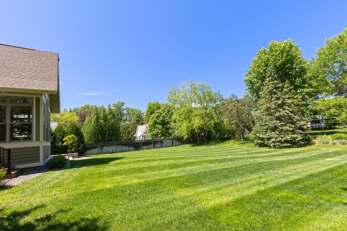 Manicured lawn surrounded by lush greenery creates an inviting outdoor space.