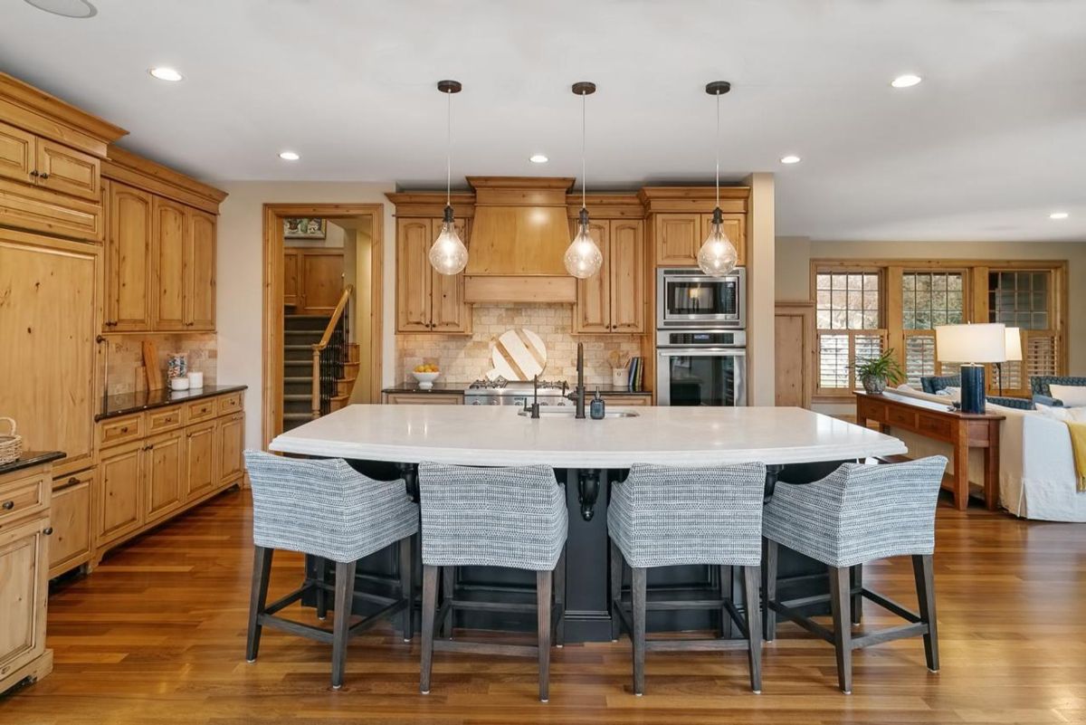 Kitchen highlights a large center island with seating, natural wood cabinetry, and stylish pendant lighting.