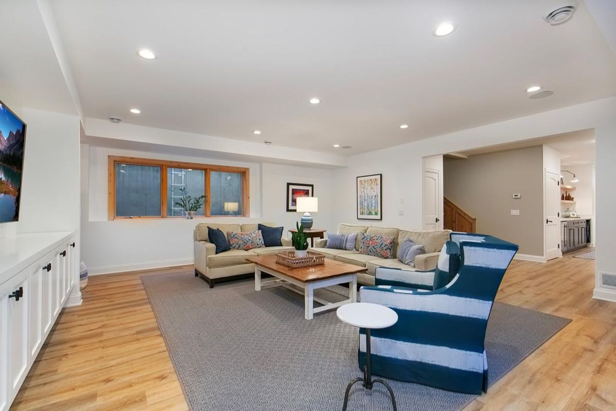 Spacious basement features comfortable seating, wood flooring, and access to additional living spaces.