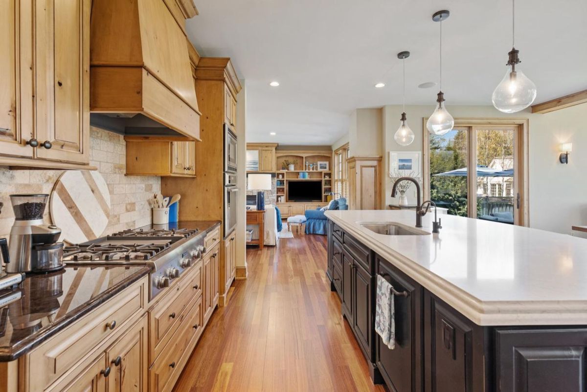 Chef's kitchen includes a professional-grade range, expansive island with sink, and custom wood cabinetry.