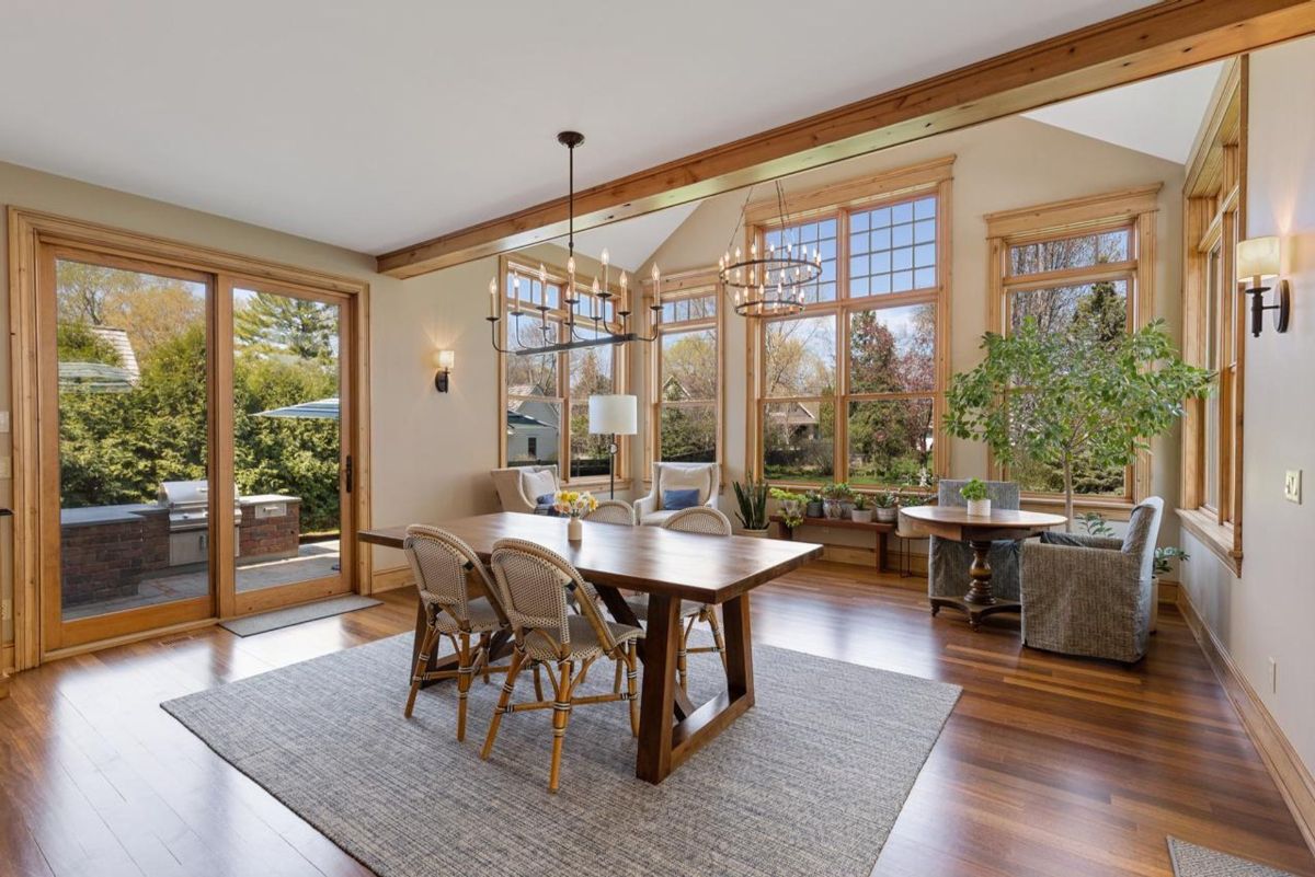 Bright dining area integrates natural light, high ceilings, and garden views with access to an outdoor kitchen.