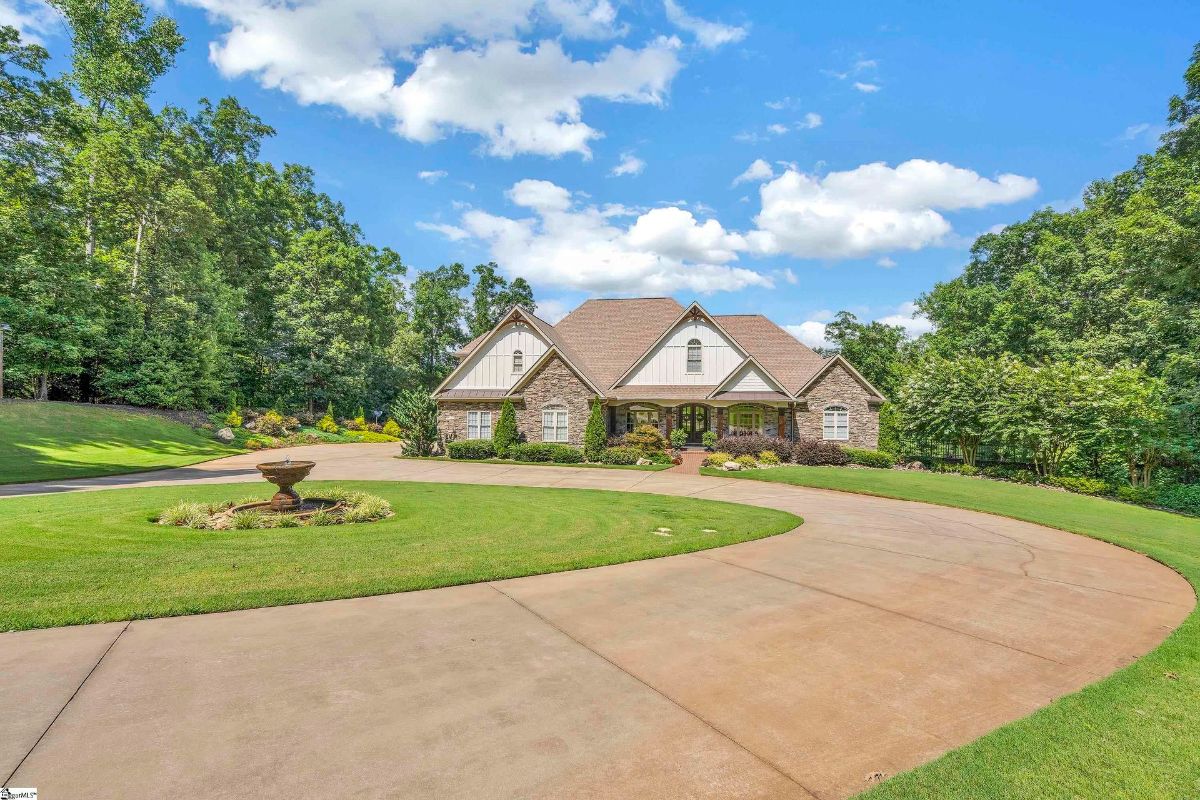 A stately residence showcases classic architectural charm, framed by manicured lawns and a circular driveway.