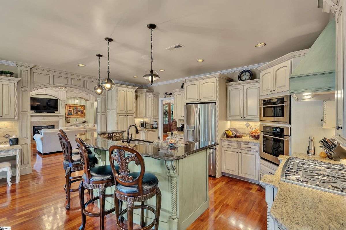 The kitchen boasts custom cabinetry, stainless steel appliances, and a spacious island with a curved breakfast bar, perfect for casual meals or entertaining.