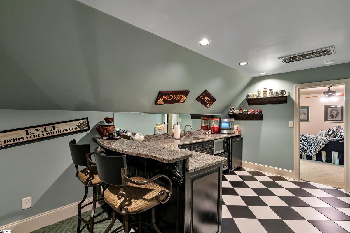 Entertainment room features a retro-style wet bar with granite counters and theater-themed decor, perfect for hosting movie nights.