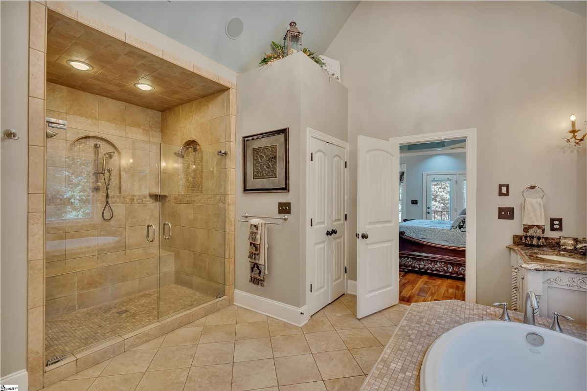 Bathroom features a spacious walk-in shower with dual showerheads and warm tile detailing, complemented by a soaking tub for ultimate relaxation.