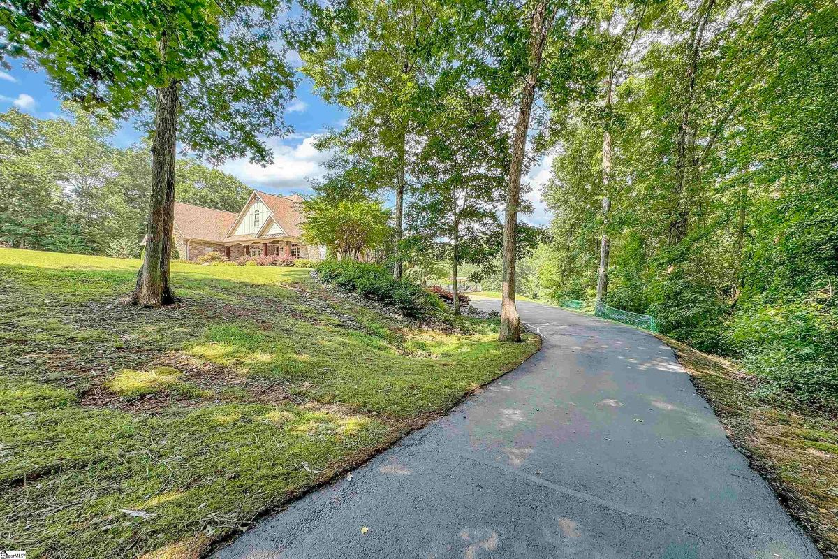 A tree-lined driveway gently leads to a picturesque home nestled among lush greenery.