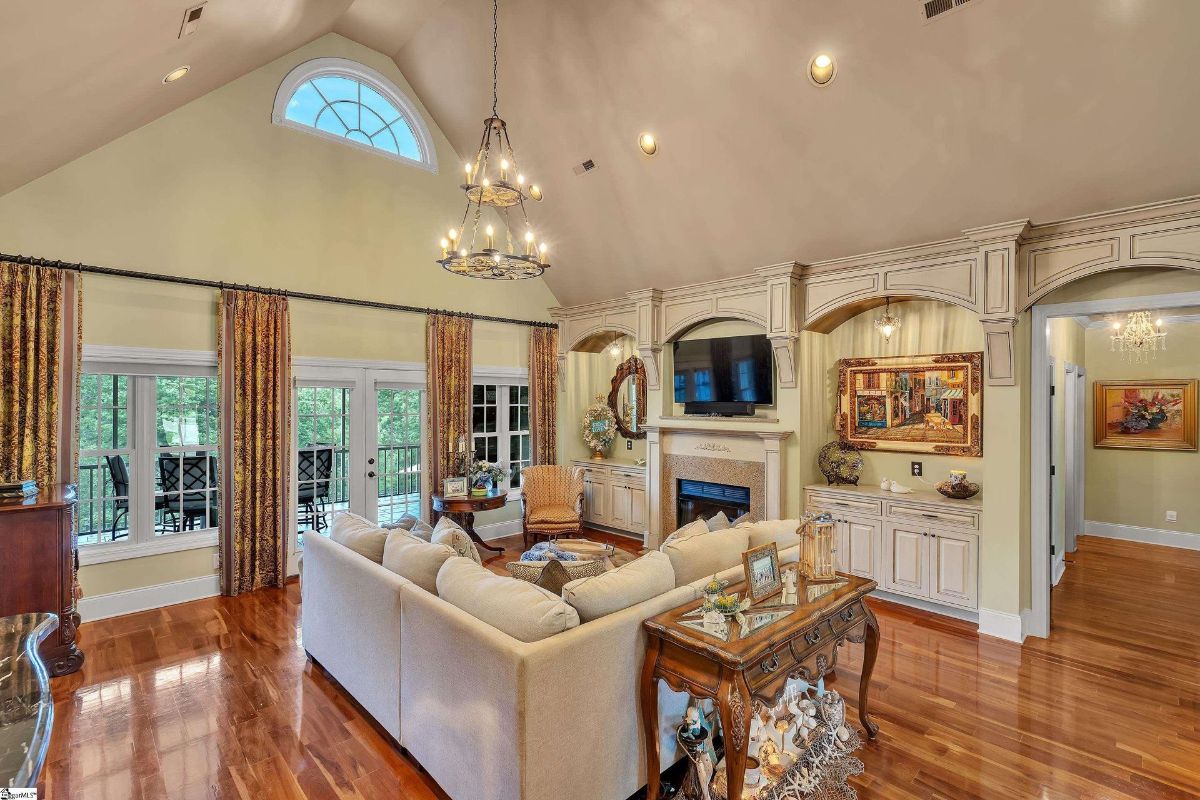 Great room showcases soaring vaulted ceilings, an elegant chandelier, and expansive windows leading to a spacious outdoor balcony.