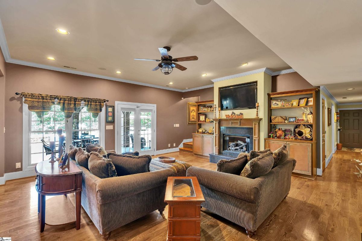 The cozy den features rich wood floors, a central fireplace with a custom mantle, and built-in shelving.