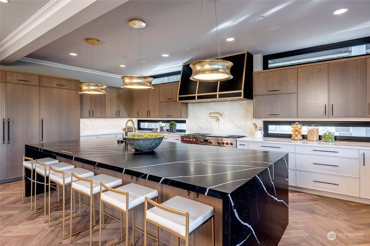 Modern kitchen with a large island featuring a dramatic black and white marble countertop. 