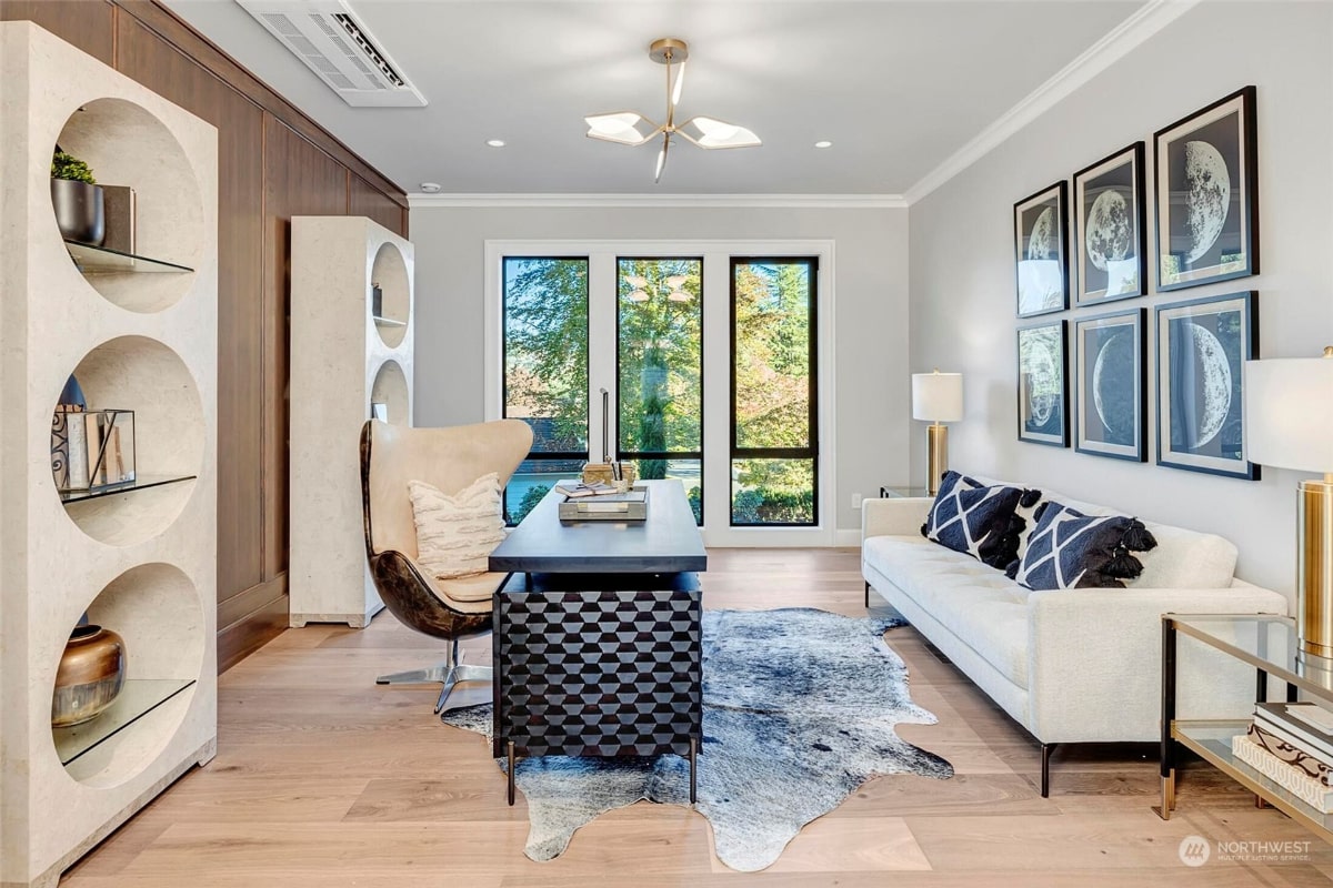 Home office or study with a white sofa, a desk with a geometric pattern, and a unique shelving unit with circular cutouts.