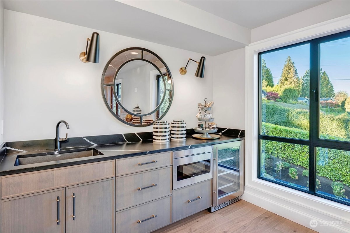 Stylish wet bar or kitchenette with light gray cabinets, a dark countertop, and a built-in wine cooler. 