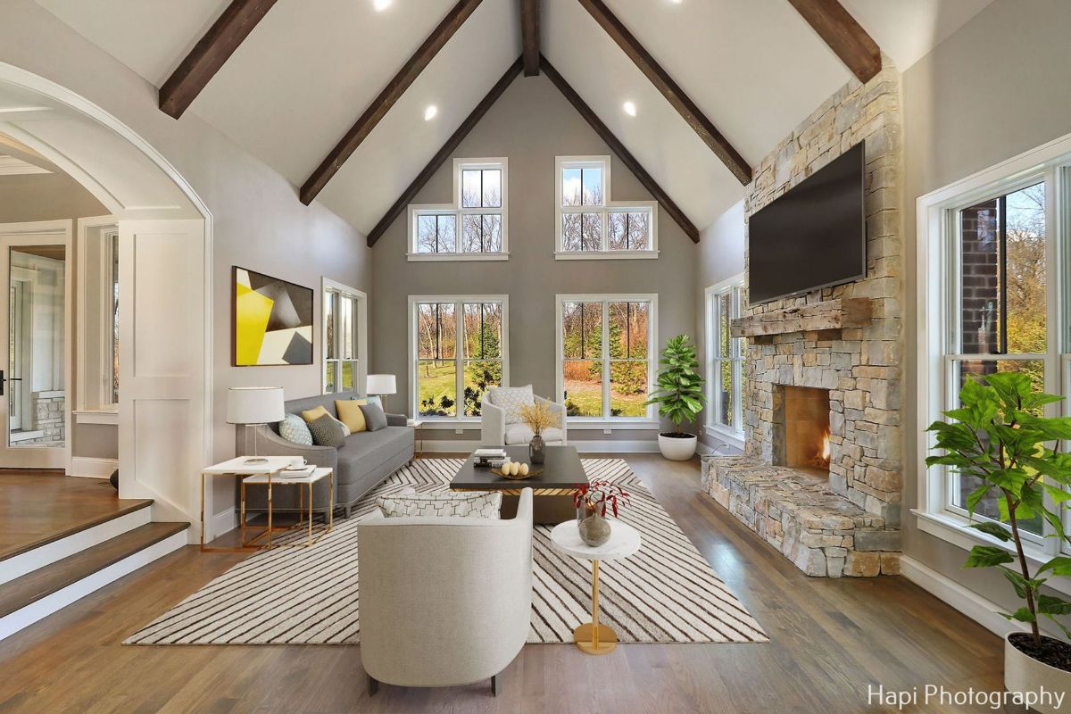 A large stone fireplace is a focal point, and several windows offer abundant natural light and views of the outdoors.