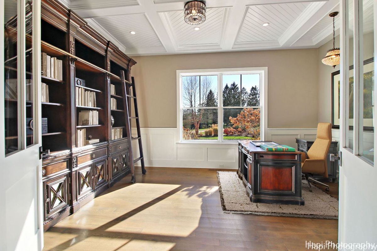 Home office with a large, ornate wooden bookcase, a substantial desk, and a comfortable armchair.