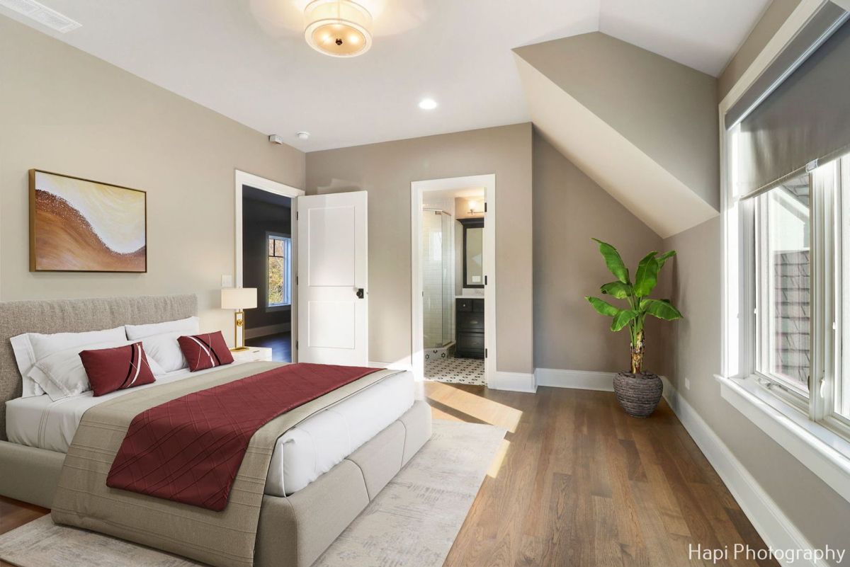 A bedroom with a maroon-colored throw, and an ensuite bathroom features a calm and sophisticated design.