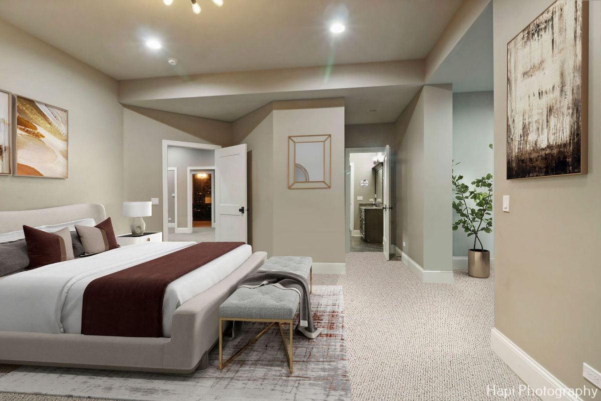 Master bedroom with a large bed, a plush bench at the foot of the bed, and an ensuite bathroom showcases a sophisticated and elegant design.