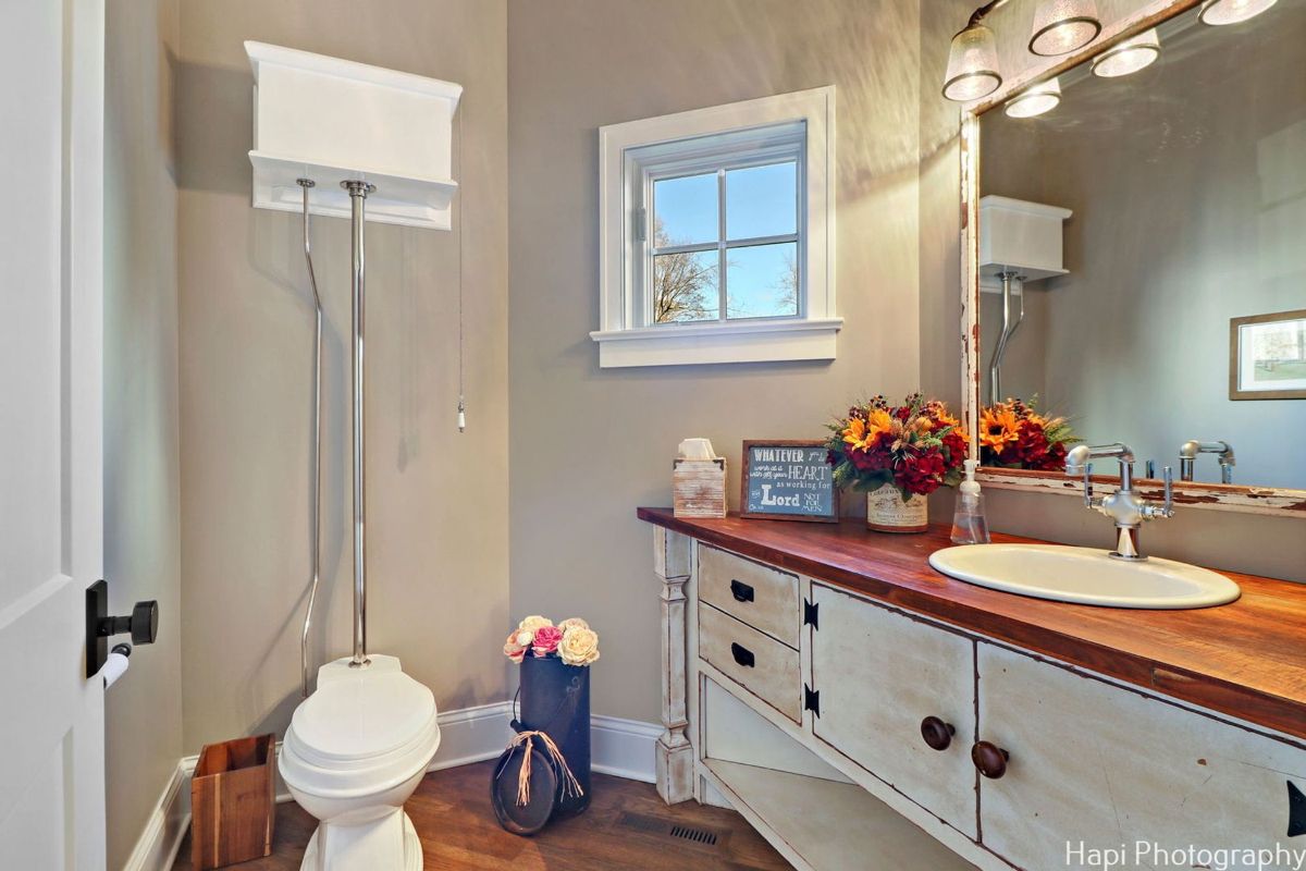 Powder room with a vintage-style toilet, a rustic vanity with a wood countertop, and a window