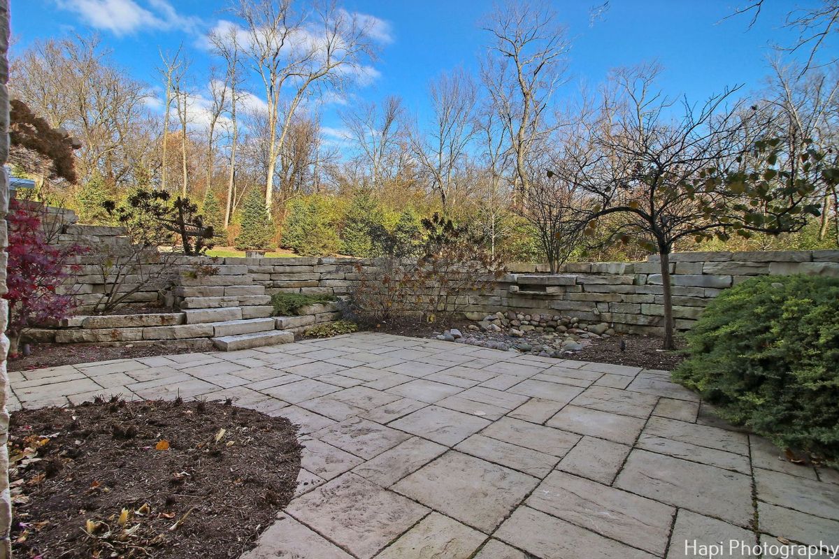 Stone patio with a retaining wall and steps provides a sophisticated outdoor space.