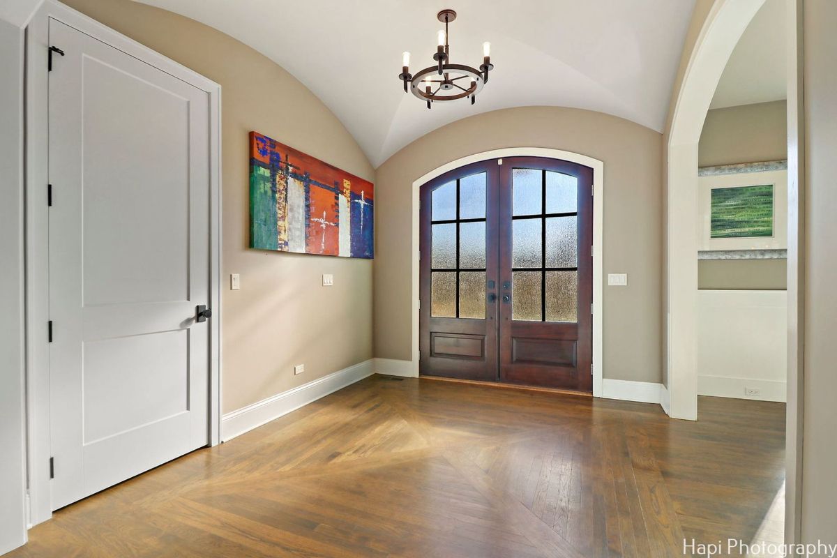 Foyer with hardwood floors, a large double door entryway with frosted glass panels, and an abstract painting on the wall.