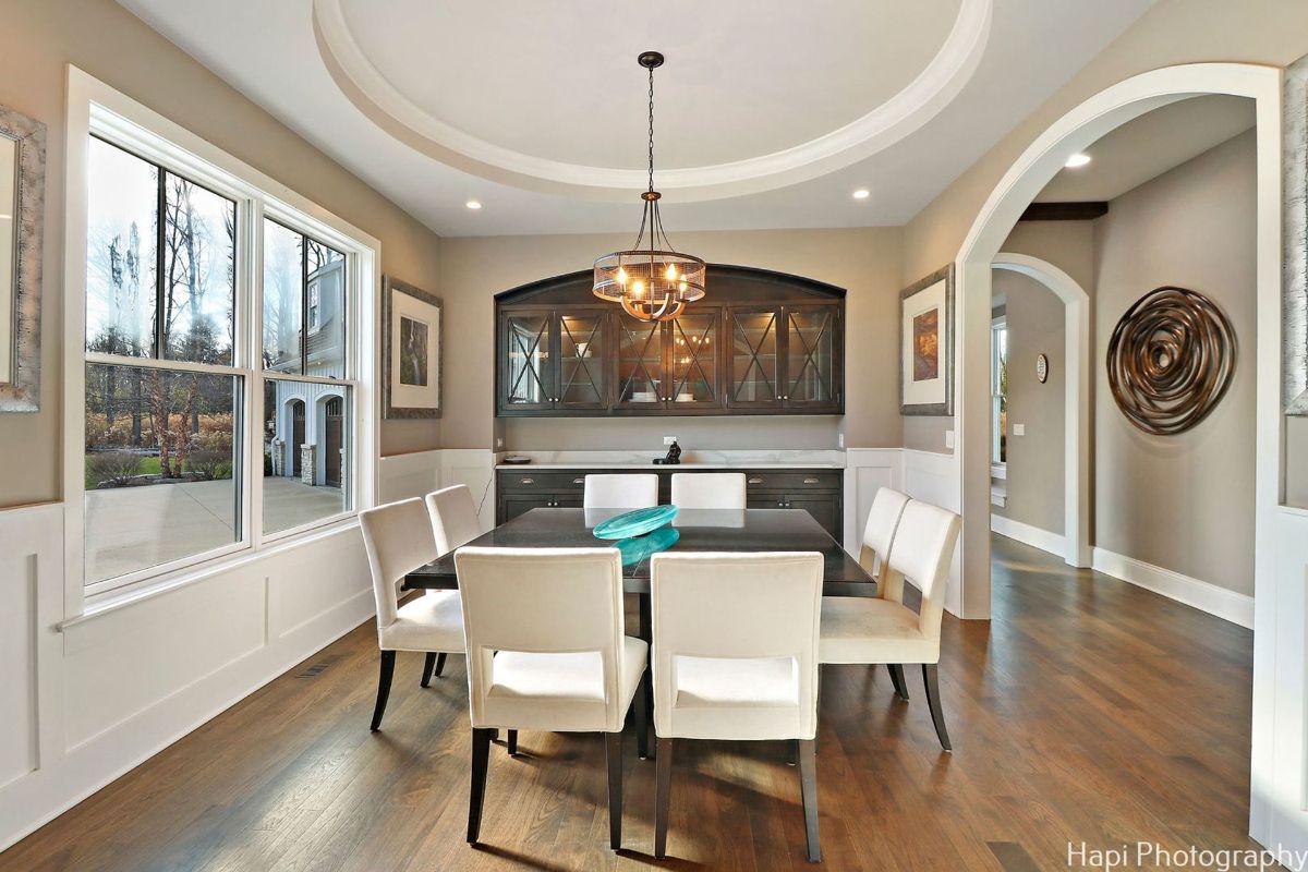 Formal dining room with a large wooden table surrounded by white chairs.