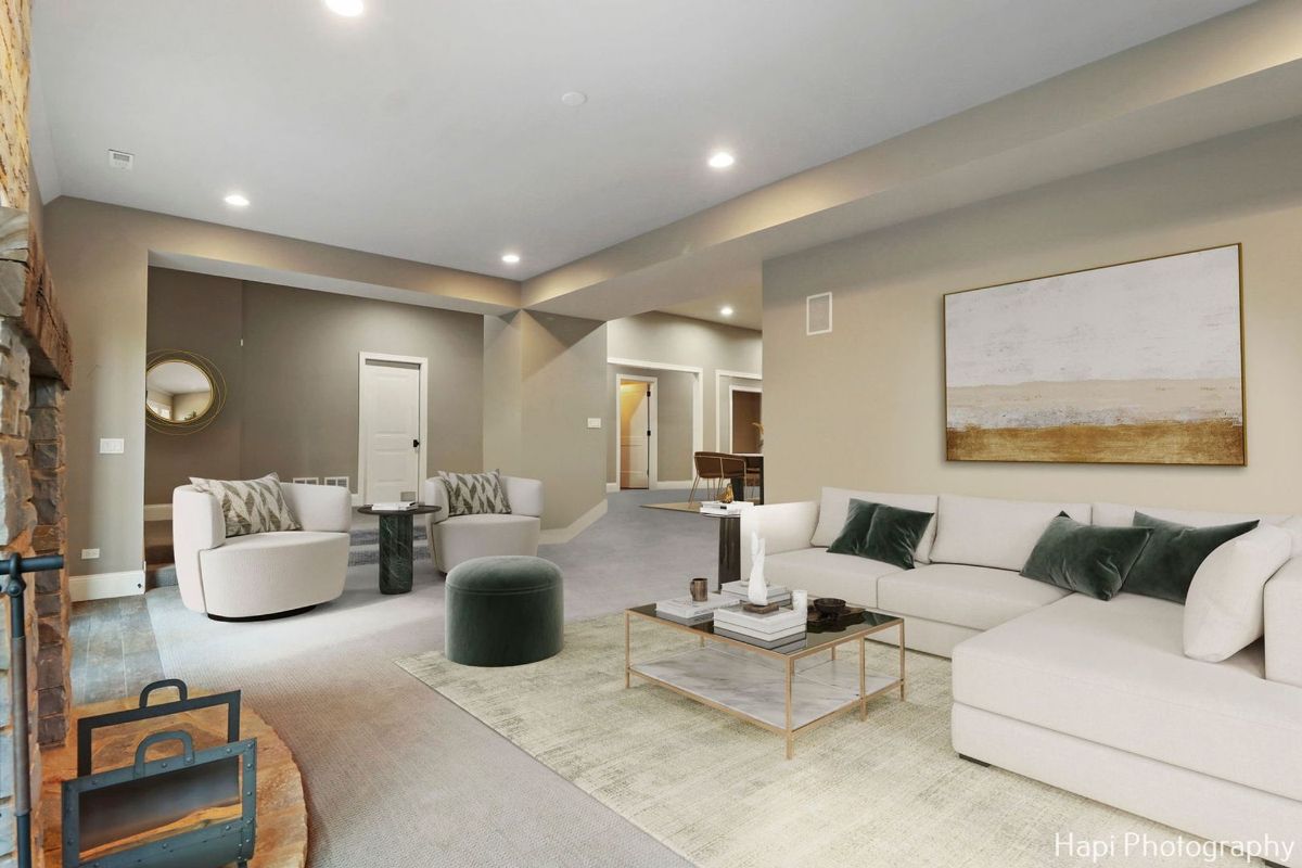 Basement recreation room with a large sectional sofa, armchairs, a coffee table, and an area rug.