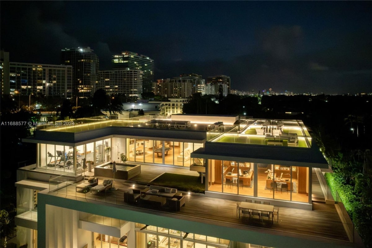 Nighttime aerial view of rooftop terrace. The terrace features what appears to be a hot tub, outdoor seating areas, and possibly an indoor space visible through large windows.