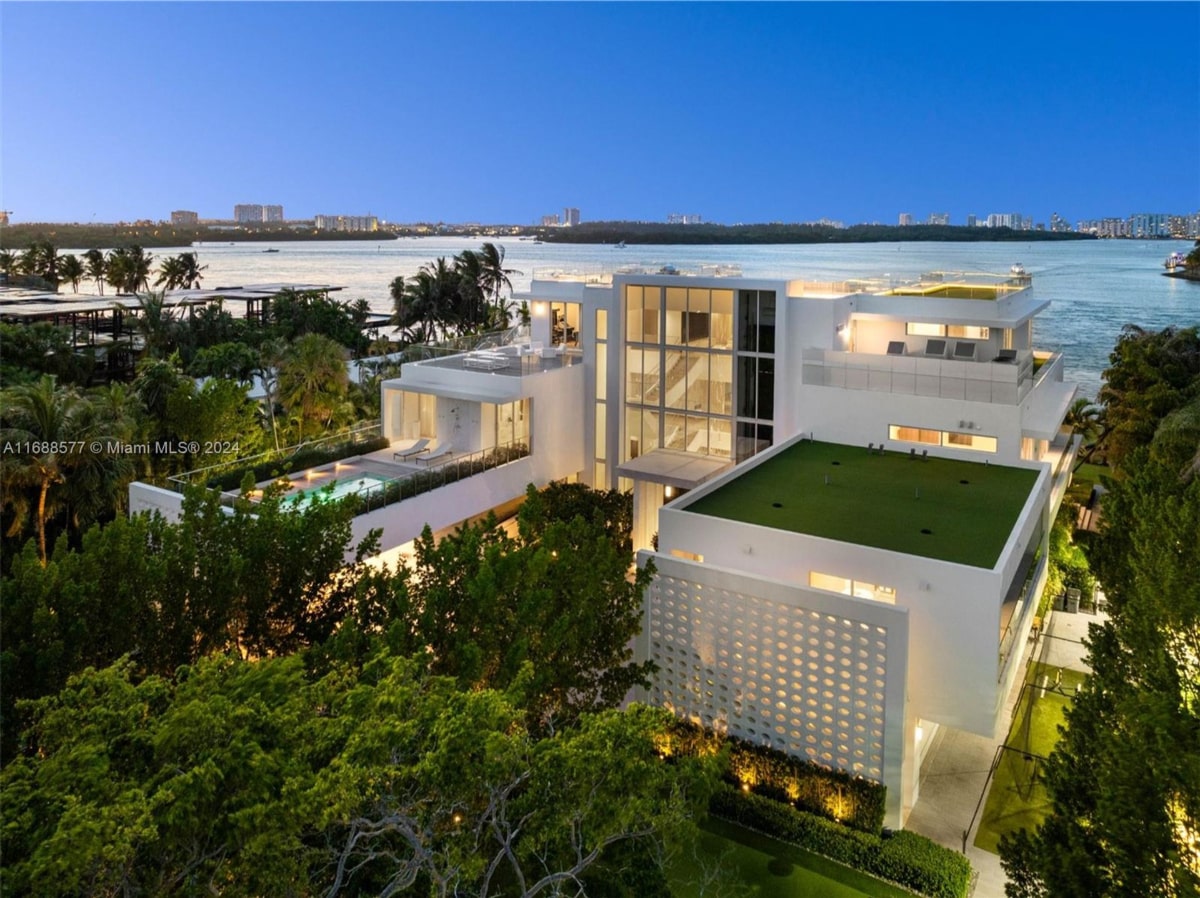 Aerial nighttime view of a modern, multi-structure home near the water.