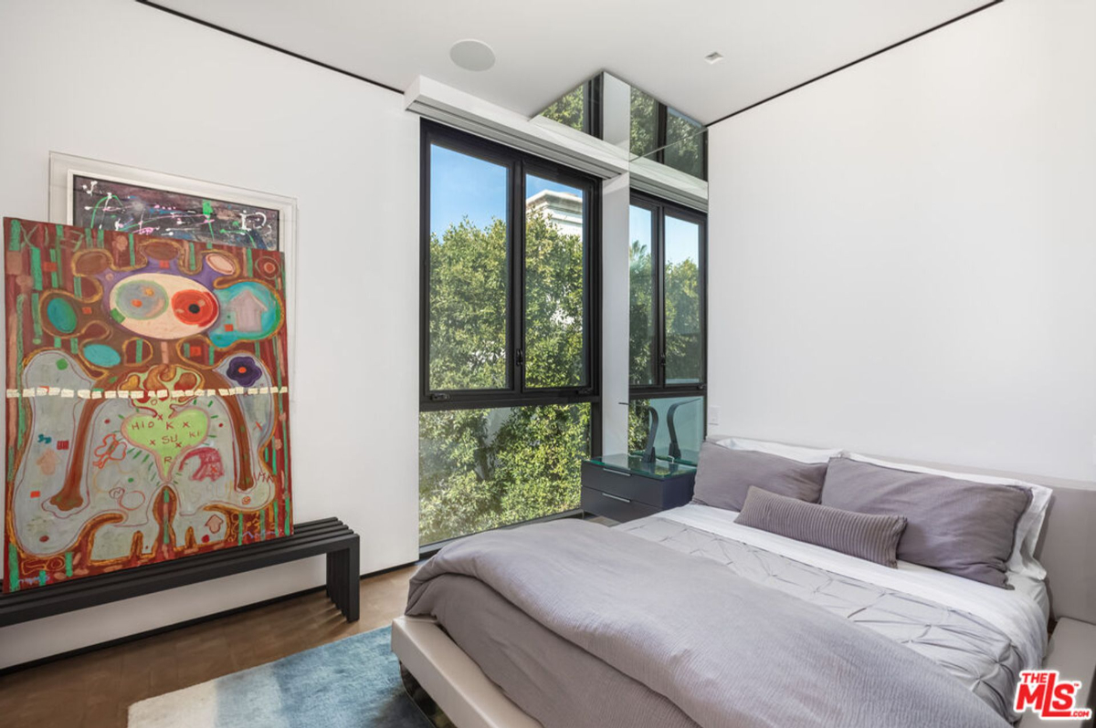 Floor-to-ceiling windows and a large piece of artwork create a focal point in this serene bedroom.