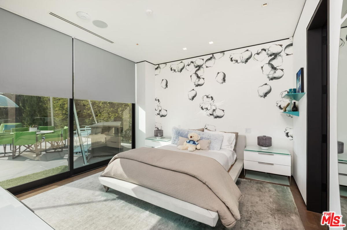 A tranquil bedroom features a unique cloud-patterned wall and outdoor access.