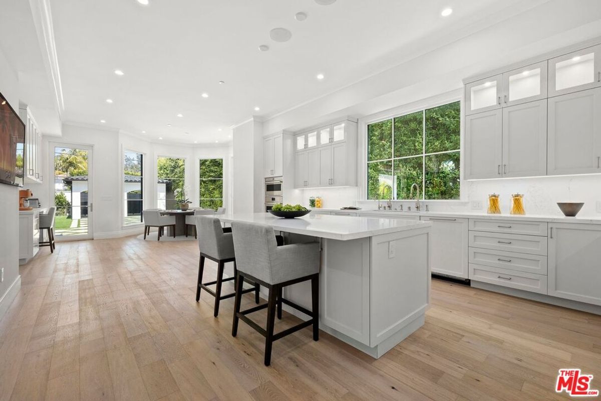 Bright, spacious kitchen features a large island, light-colored cabinetry, and plenty of natural light from large windows.