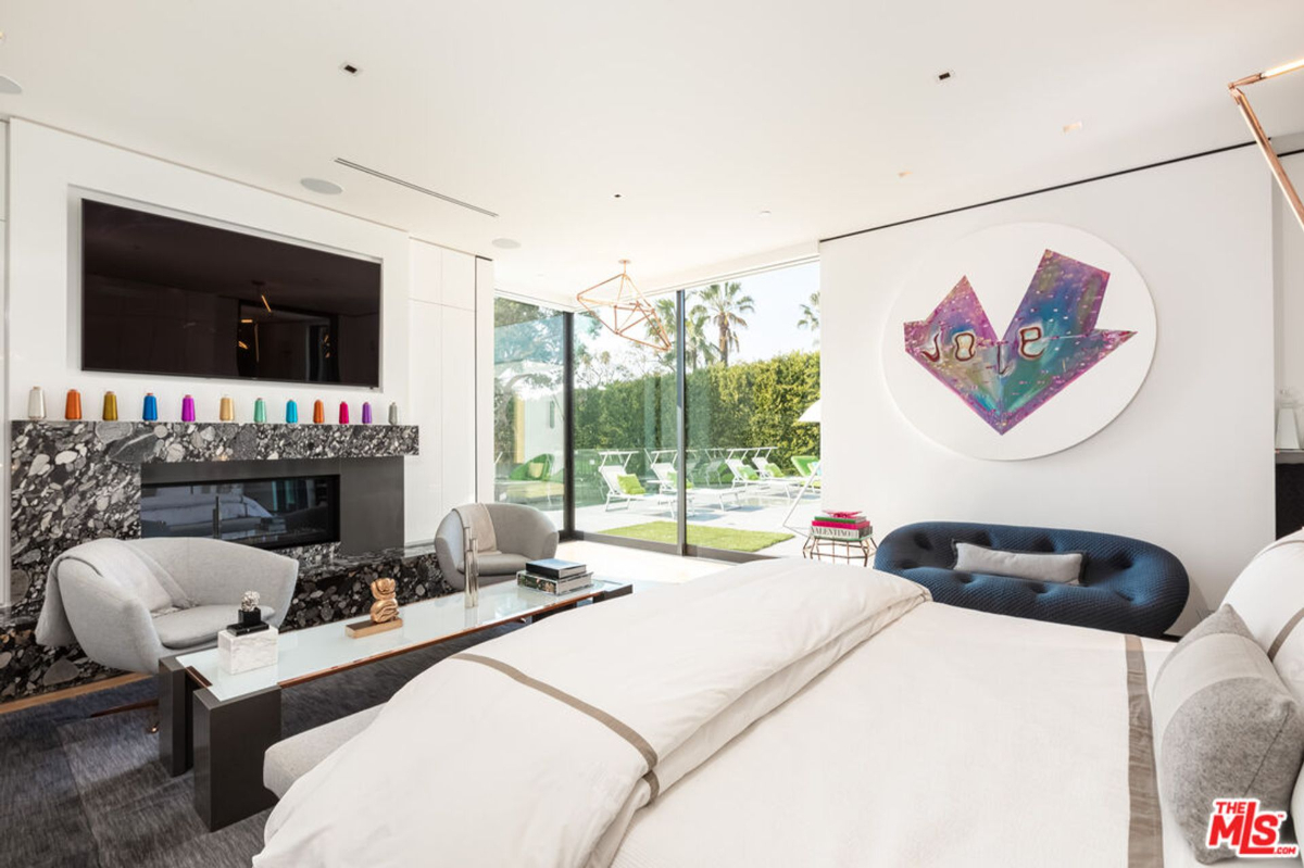 Luxurious bedroom with a fireplace, large windows, and a view of a pool.