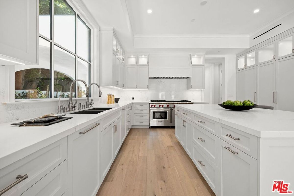 Modern kitchen with white cabinets, a large island, and stainless steel appliances. 