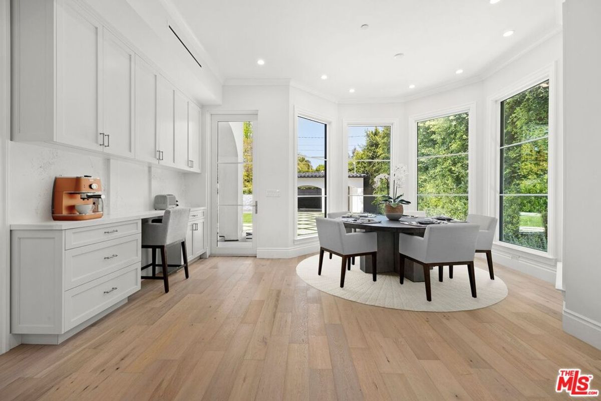 Bright breakfast nook with white cabinetry, a small table and chairs, and large windows offering a view of the outdoors.