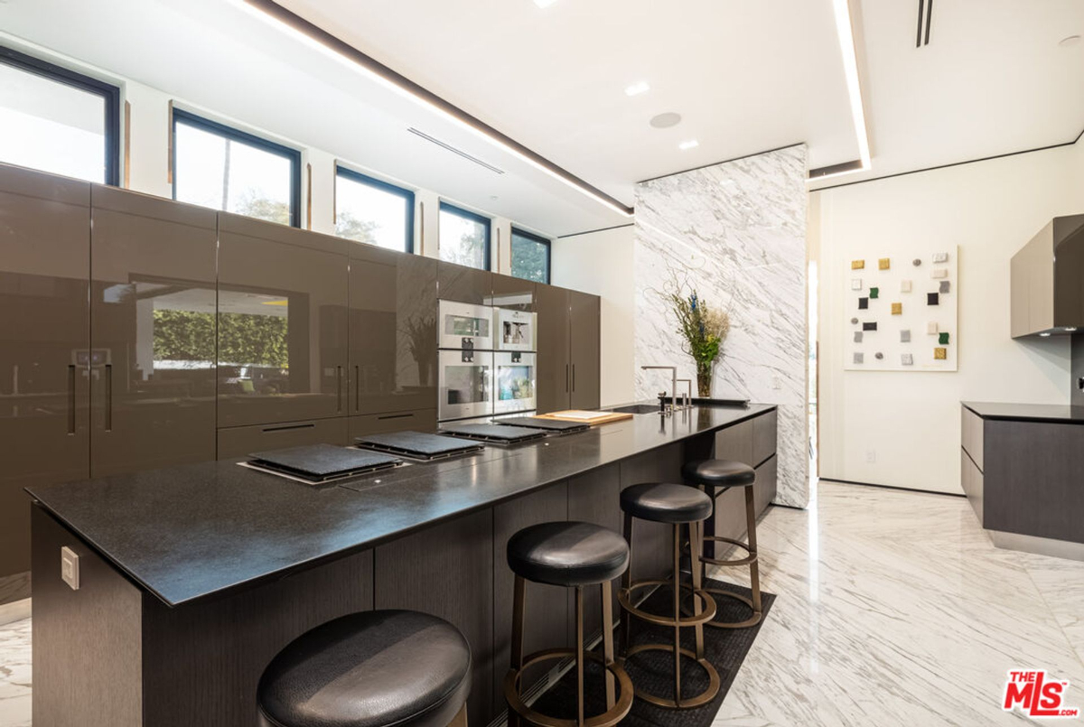 Kitchen with dark cabinetry, a large island, and marble backsplash.