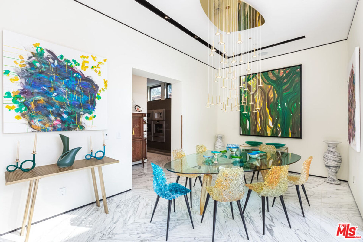 Dining room with statement artwork and unique lighting fixture.