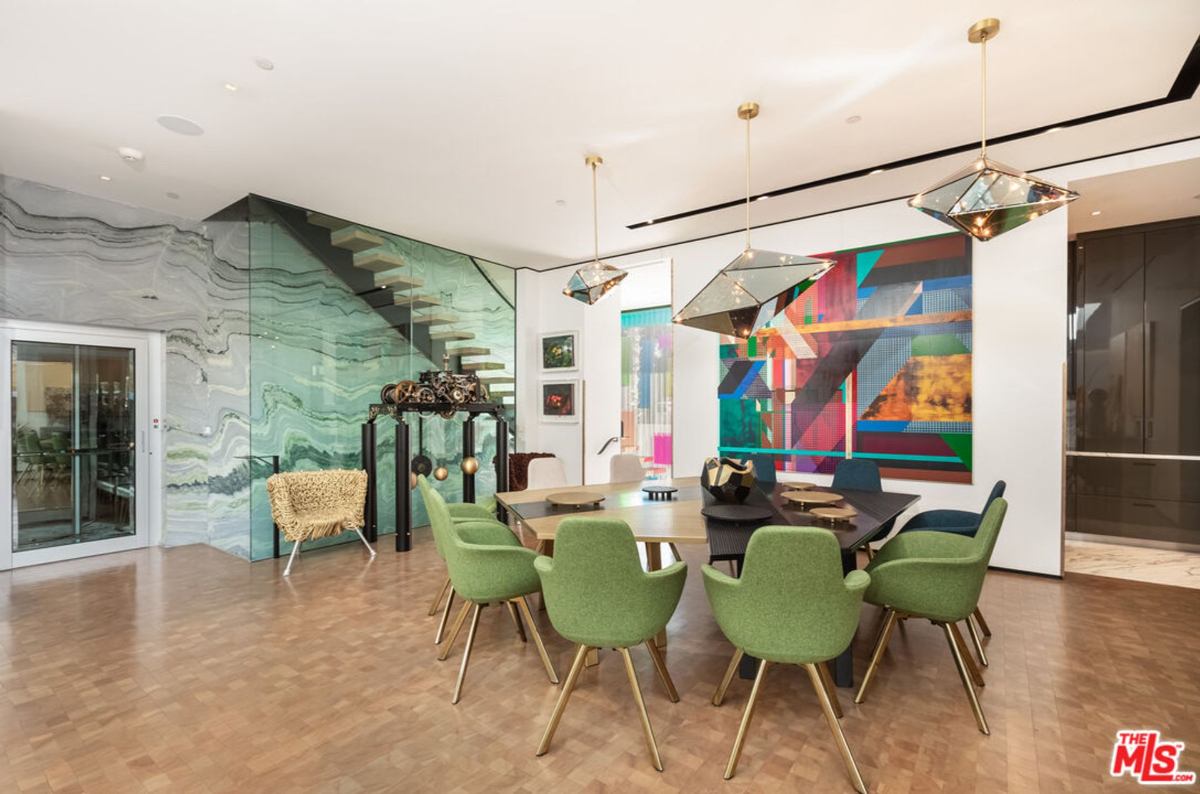 Dining area with a marble wall, statement artwork, and unique lighting.