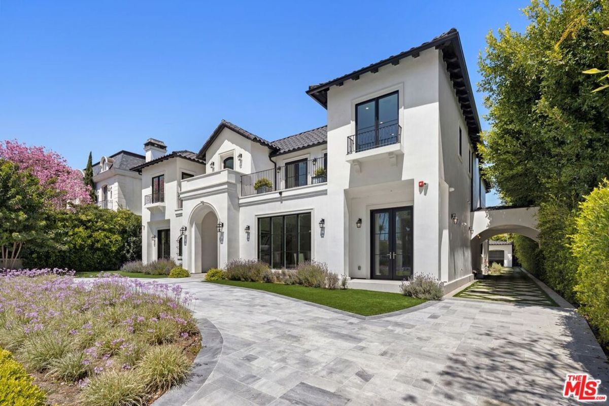 Landscaped grounds surround a large, elegant white house with a long driveway.